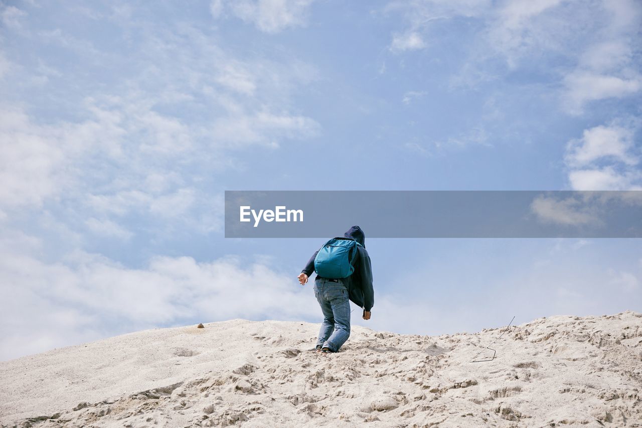 Low angle view of man climbing mountain against sky