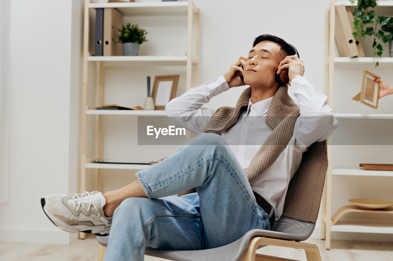 young woman using mobile phone while sitting on sofa at home