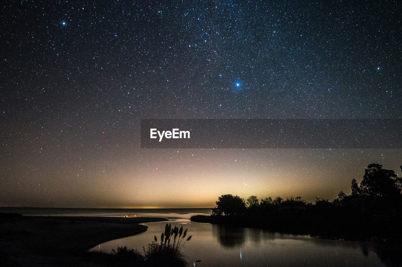 Scenic view of lake against sky at night