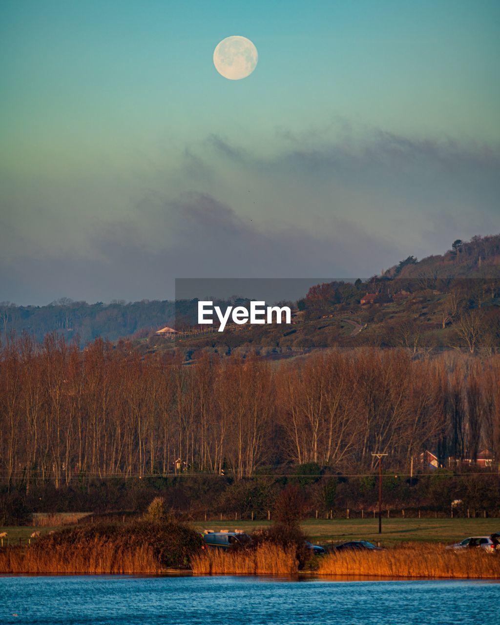 Scenic view of lake against sky and moonset