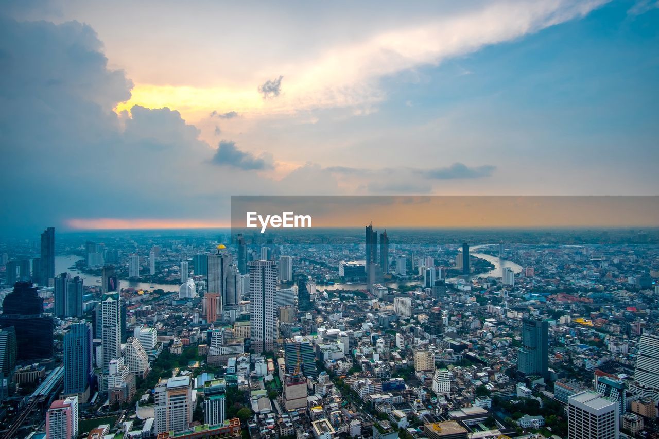 HIGH ANGLE VIEW OF ILLUMINATED BUILDINGS AGAINST SKY DURING SUNSET