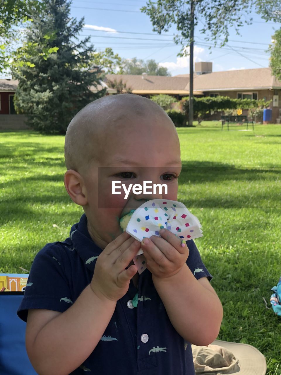 PORTRAIT OF CUTE BOY HOLDING GREEN GRASS IN PARK