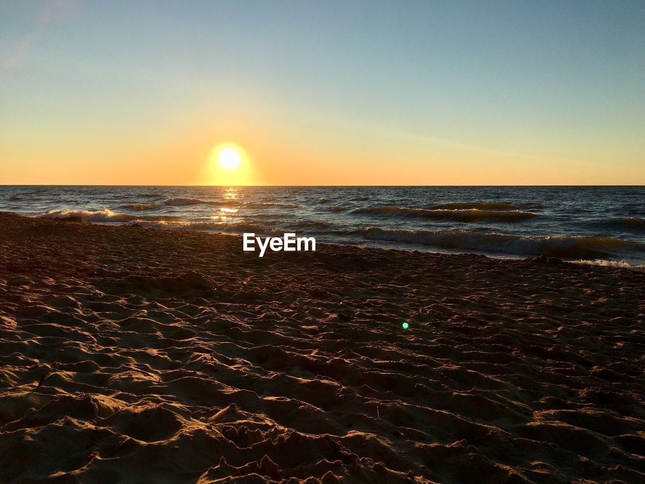 Scenic view of beach against clear sky during sunset