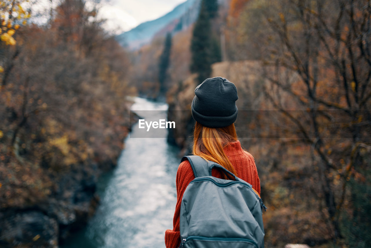 REAR VIEW OF WOMAN STANDING IN FOREST DURING WINTER