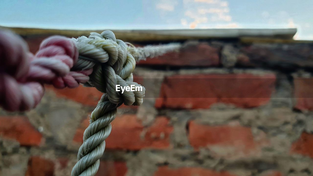 CLOSE-UP OF ROPE TIED TO METAL WALL