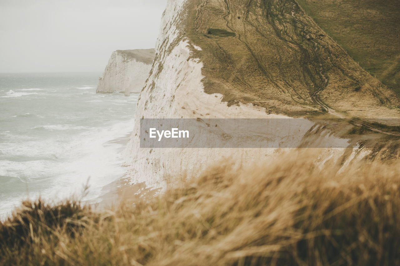 Scenic view of sea and cliff against sky