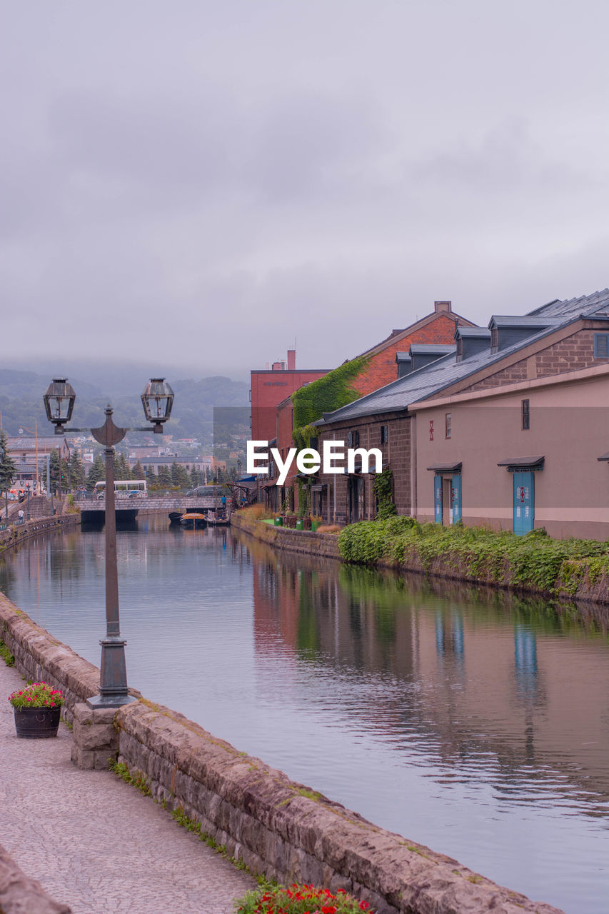 bridge over river by buildings against sky