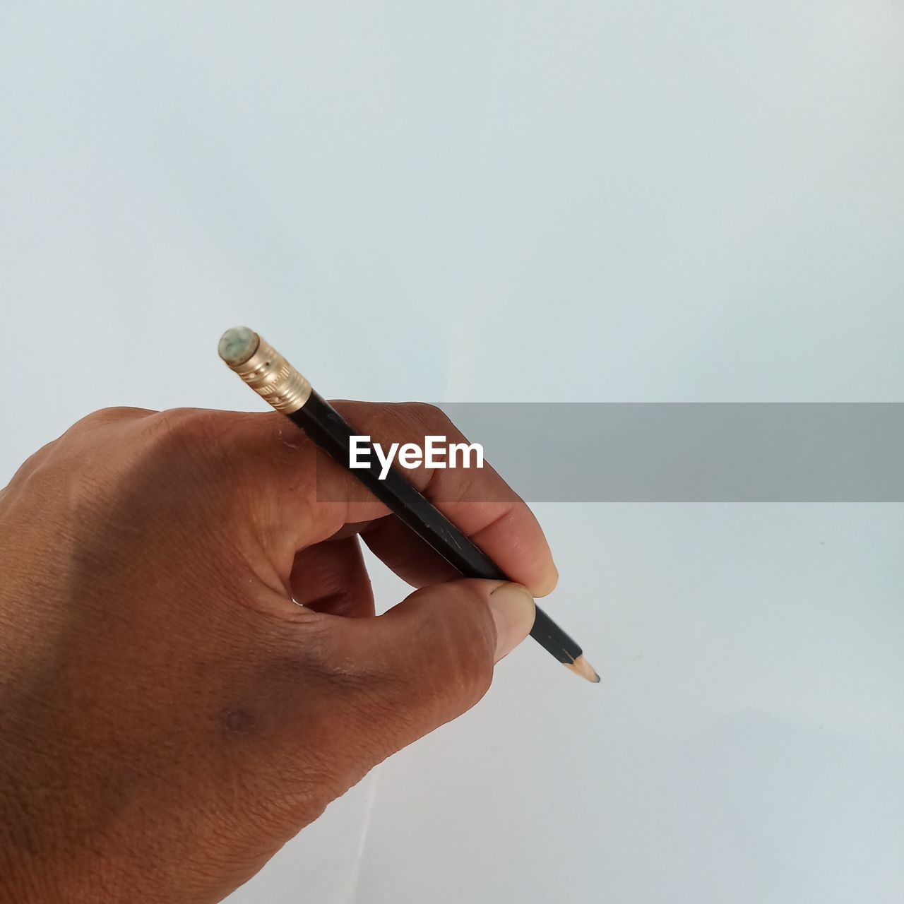 Close-up of hand holding pencil against white background