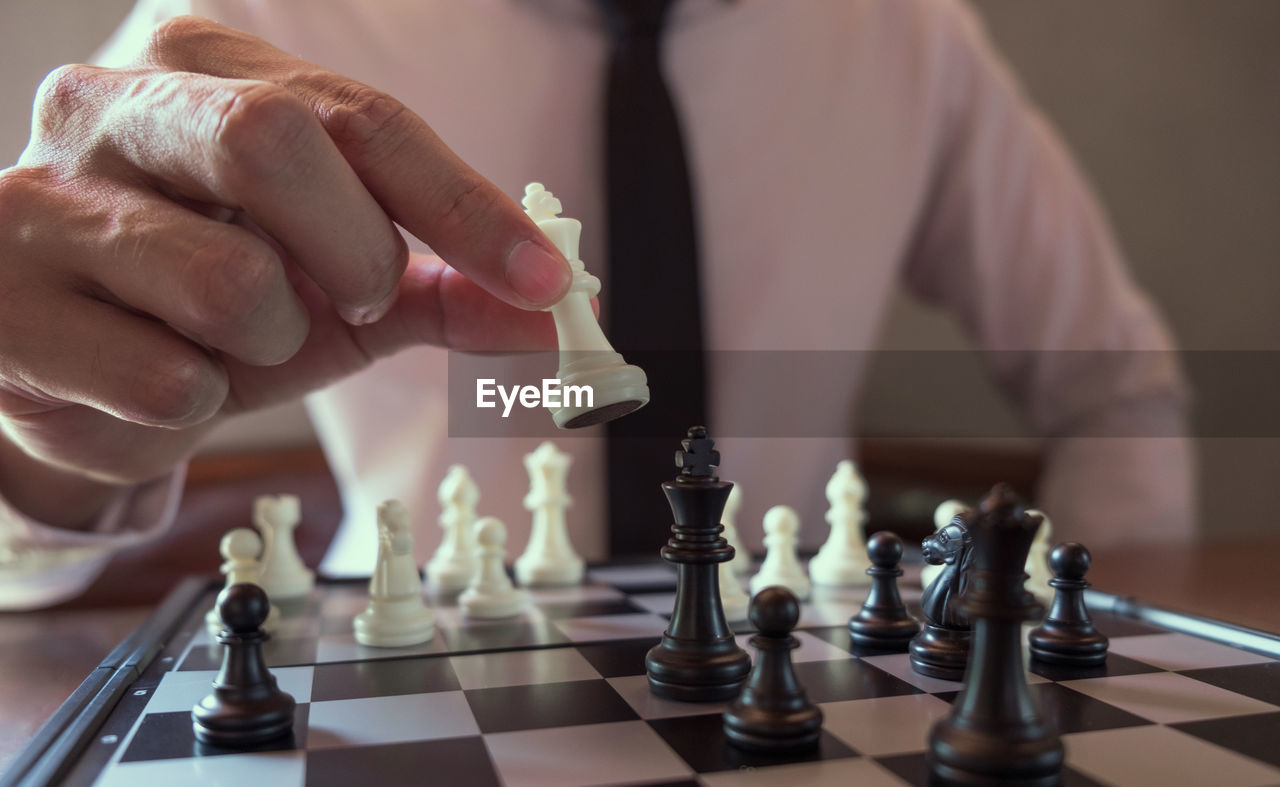 Midsection of businessman playing chess in office