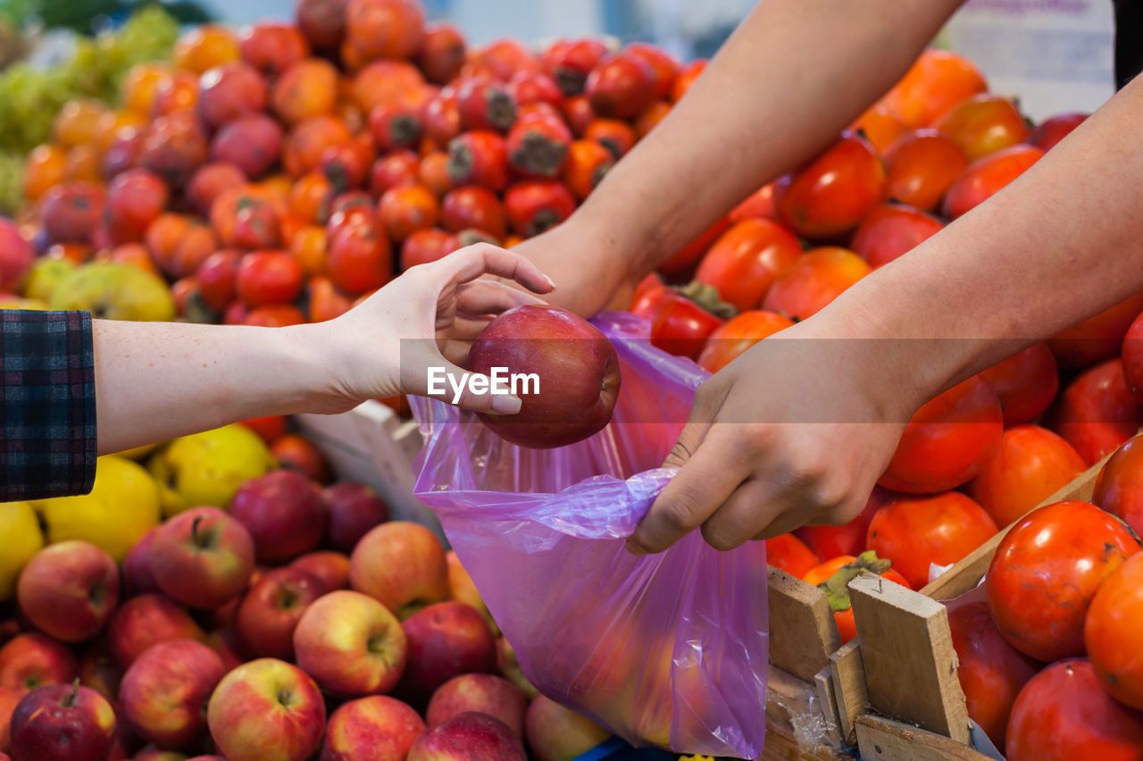 Woman buying fresh vegetables at street market.