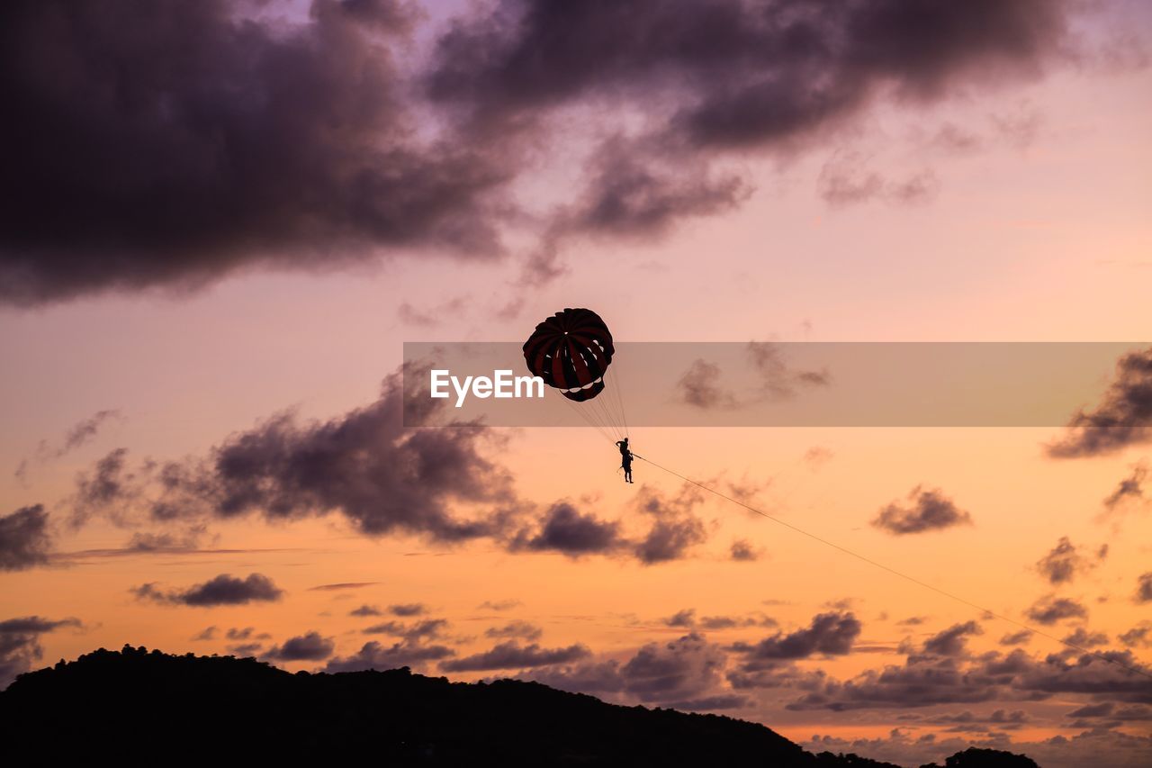 Low angle view of silhouette person parasailing against sky during sunset