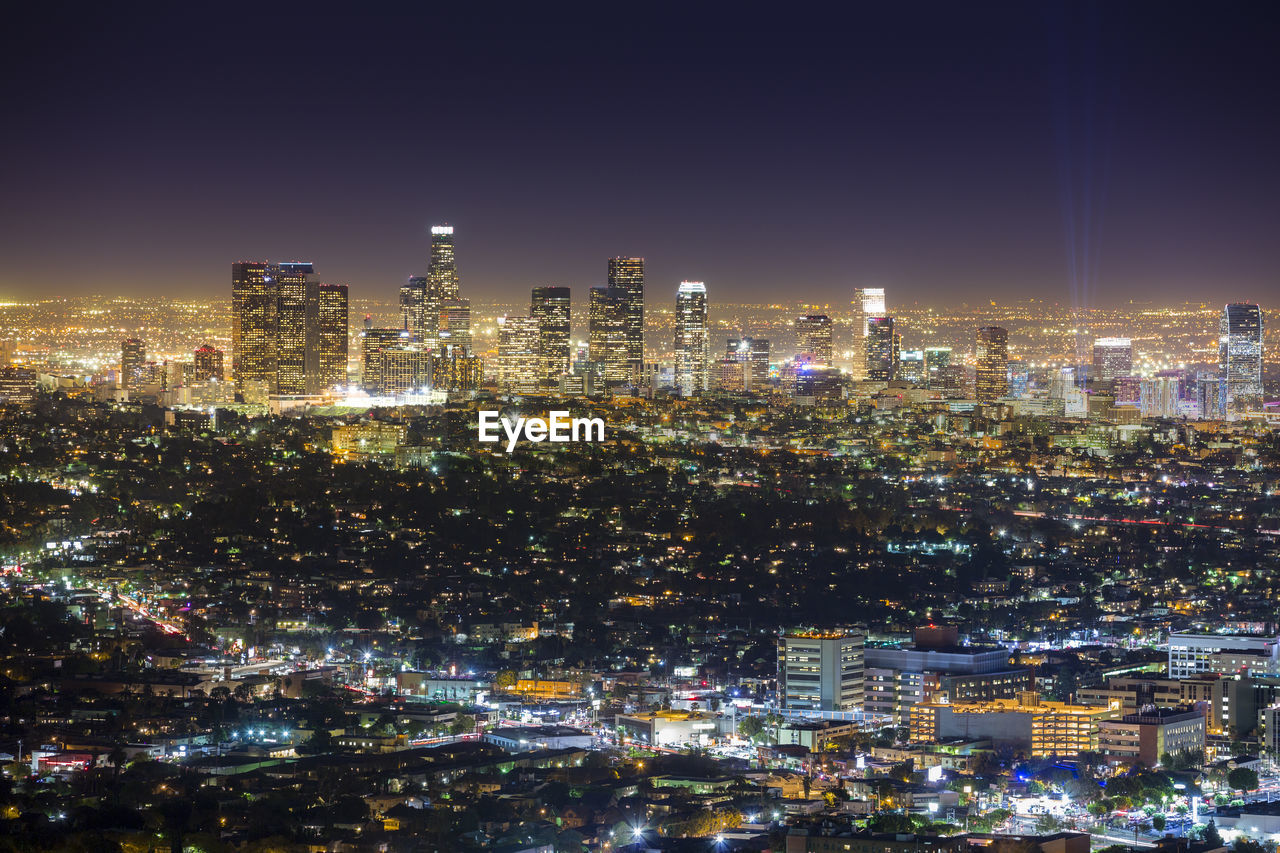 Illuminated cityscape against sky at night