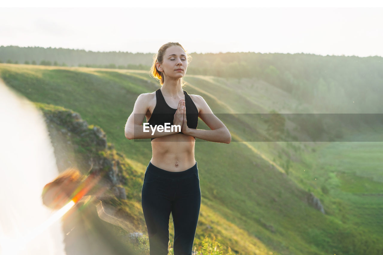 Woman meditating standing against mountain