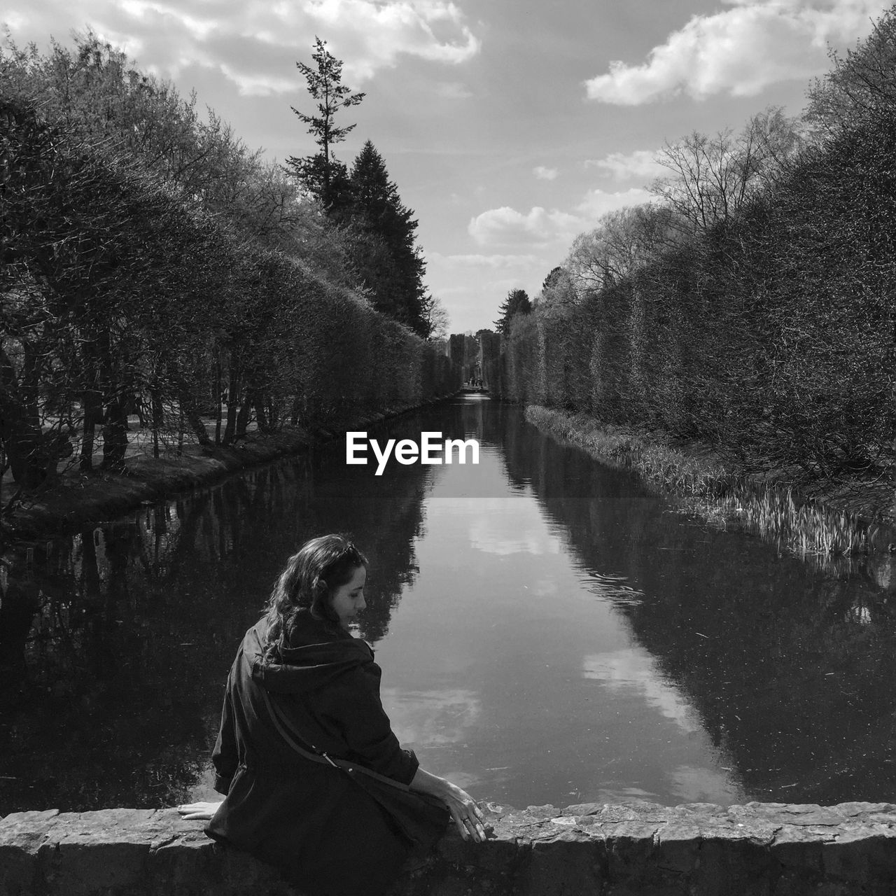 Woman sitting by park canal