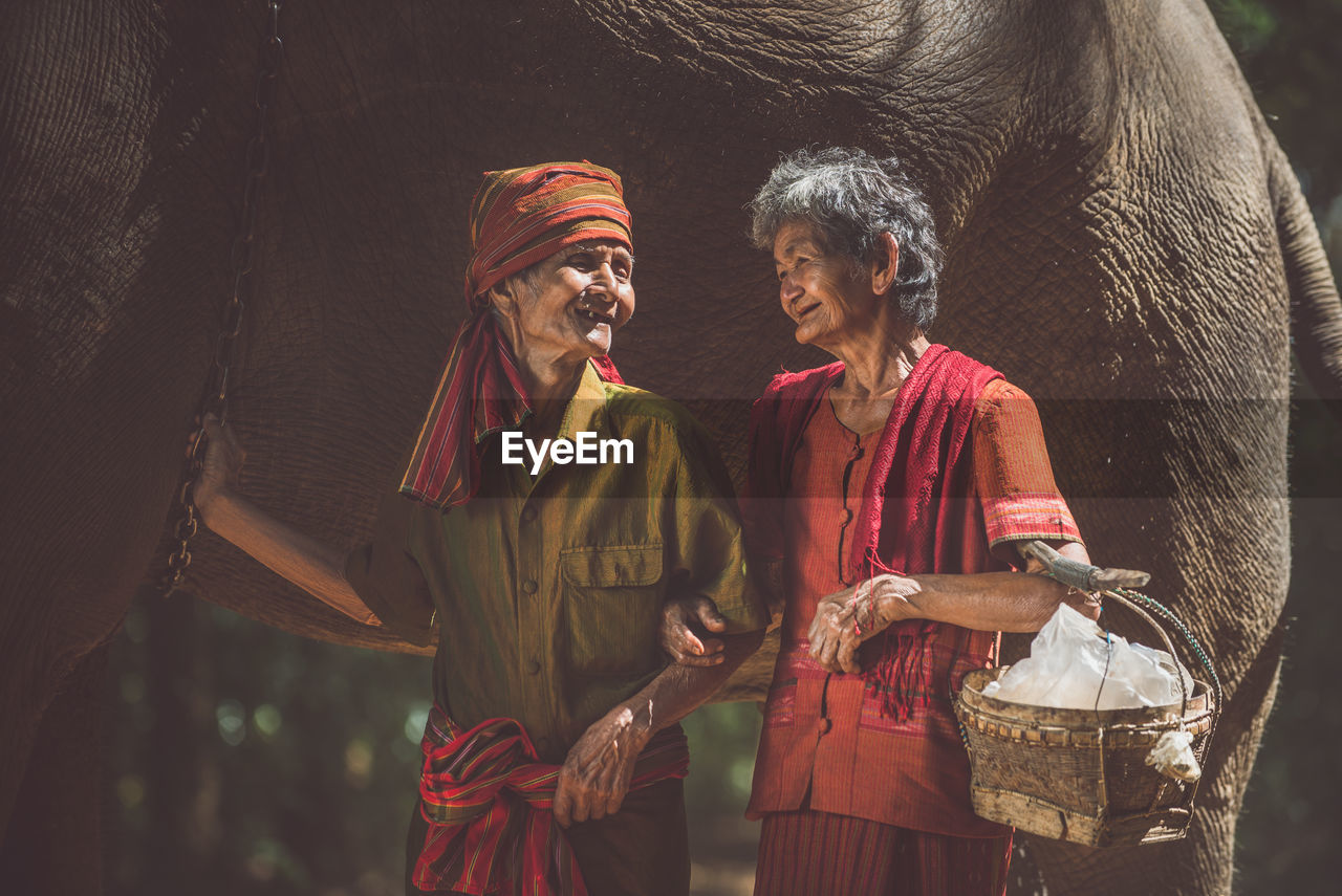 Senior couple standing by elephant in forest