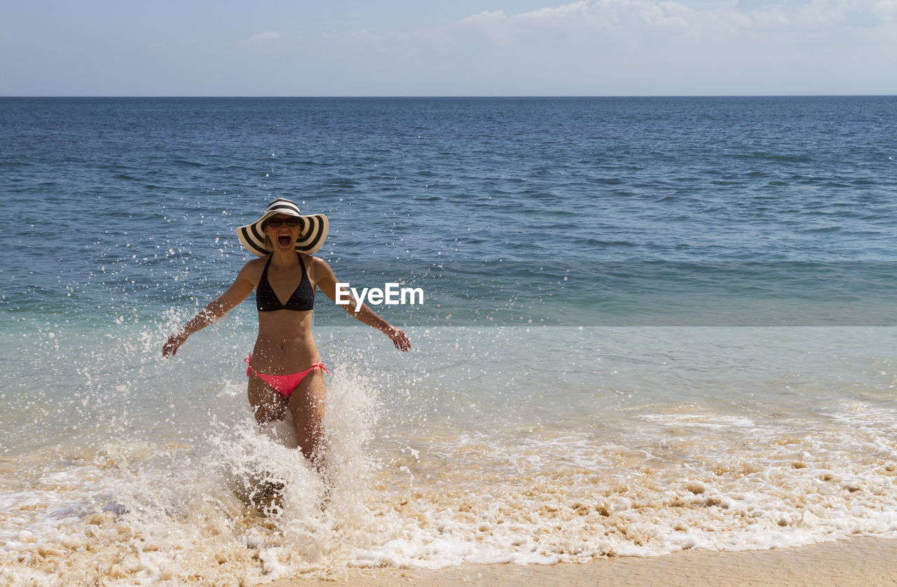 Woman standing in sea against sky