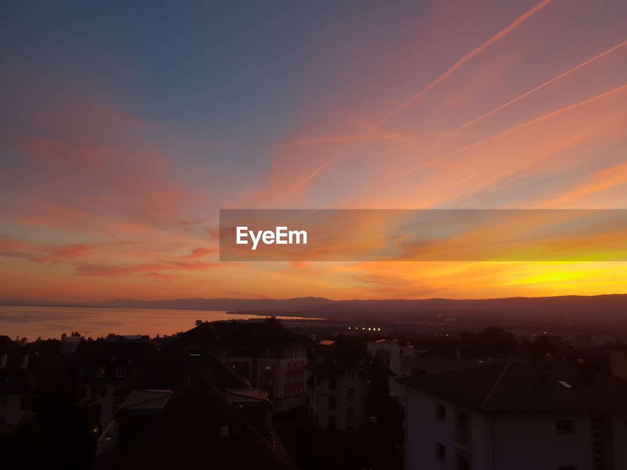 HIGH ANGLE VIEW OF ILLUMINATED BUILDINGS AGAINST SKY DURING SUNSET