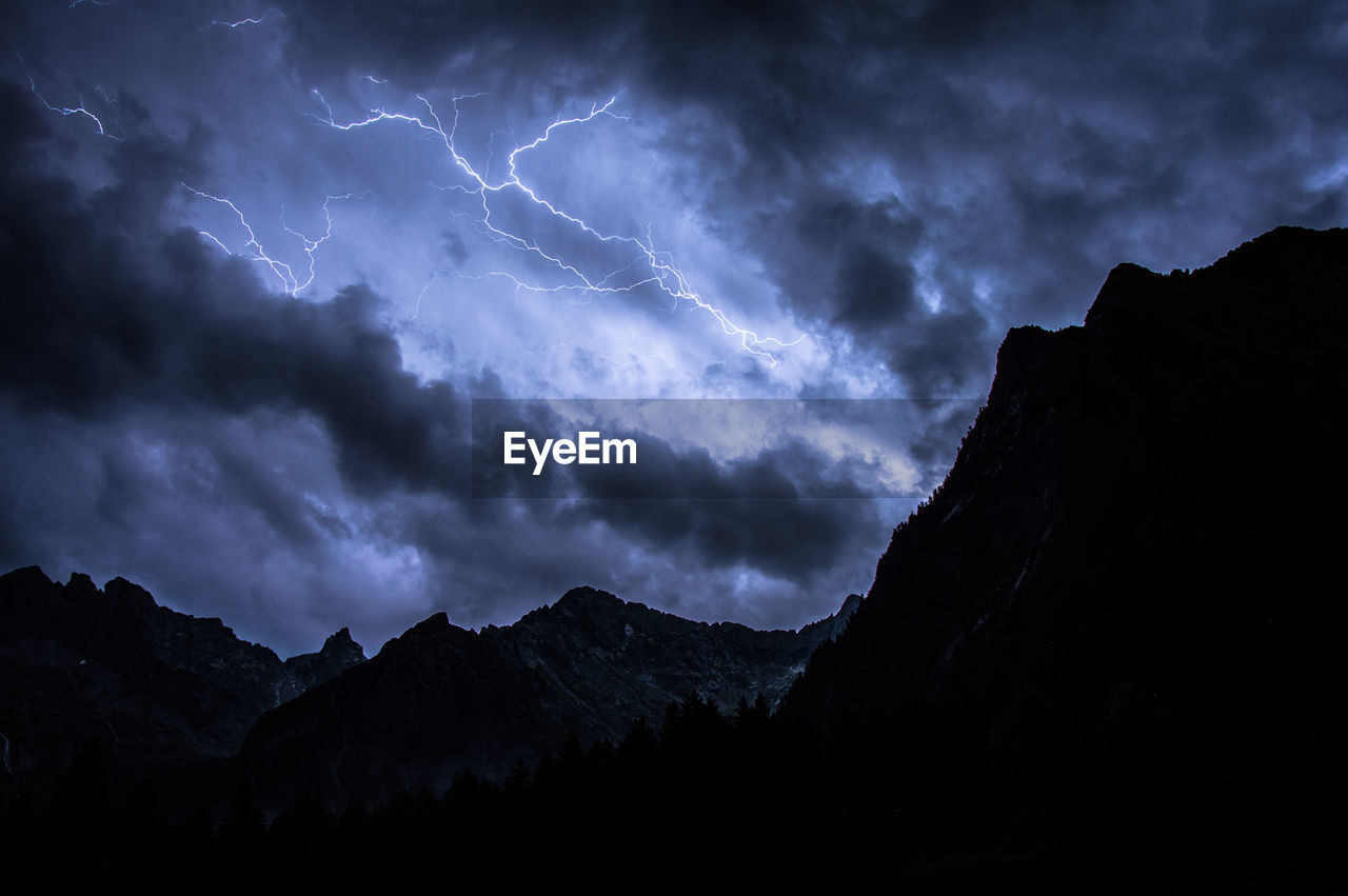 SILHOUETTE OF MOUNTAINS AGAINST SKY AT NIGHT