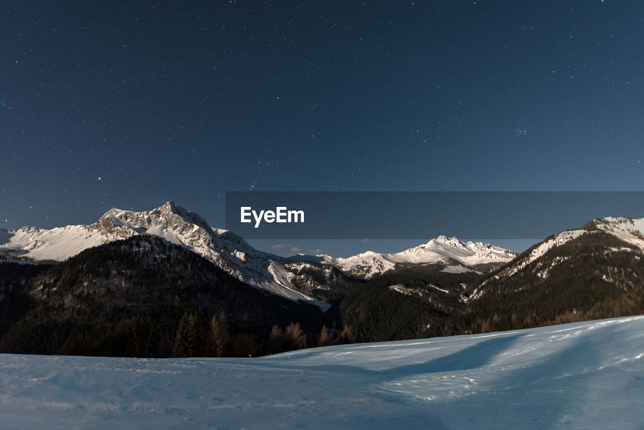 Scenic view of snowcapped mountains against sky at night