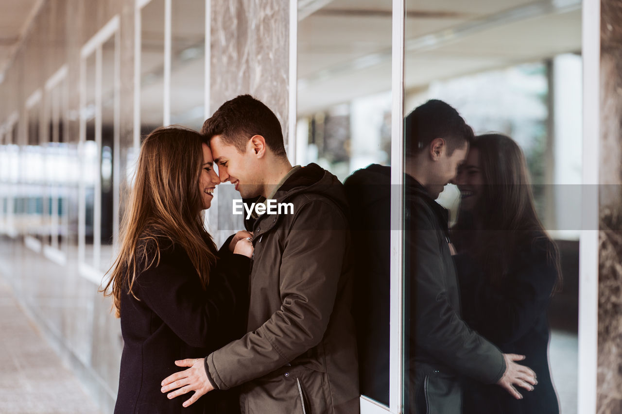 Young couple embracing against window