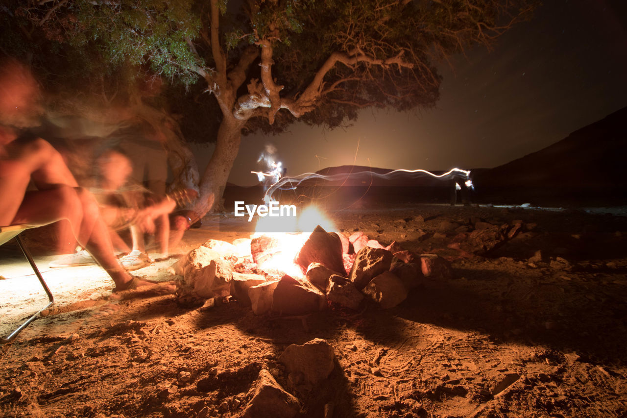 Blurred motion of people sitting by campfire in forest