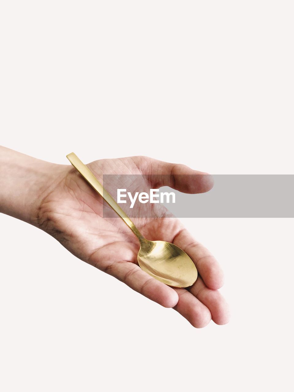 Cropped image of hand holding spoon against white background