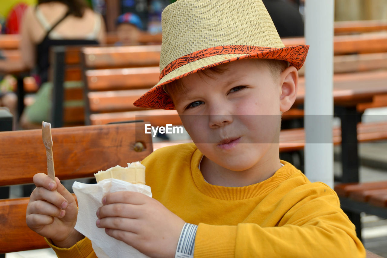 Close up image of boy hand holding fresh waffle cone with vanilla