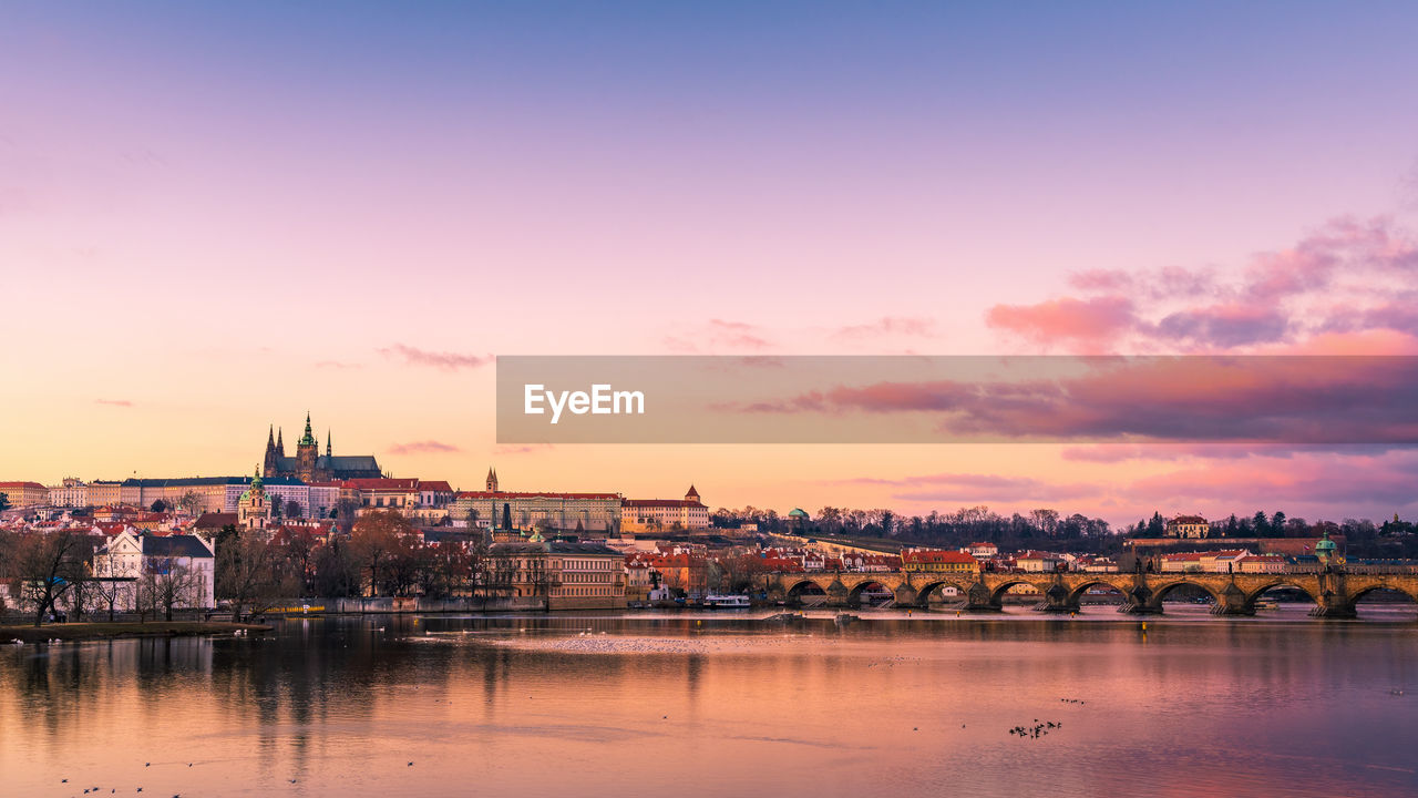 Scenic view of river and buildings against sky during sunset