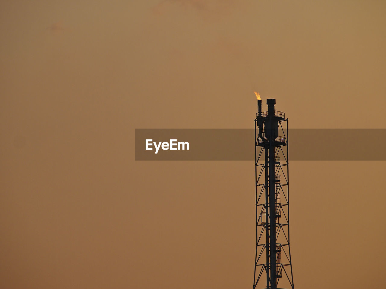 High tower of refinery in evening sky background