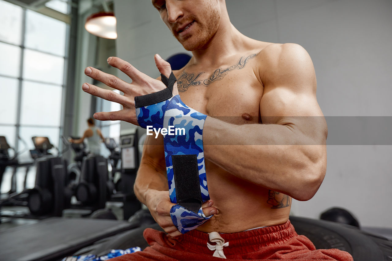 Low angle view of shirtless man exercising in gym