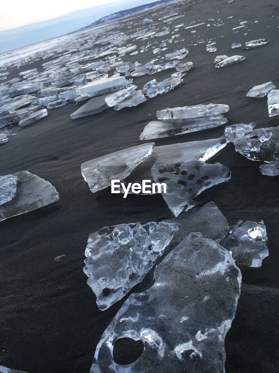 CLOSE-UP OF FROZEN BEACH AGAINST SKY