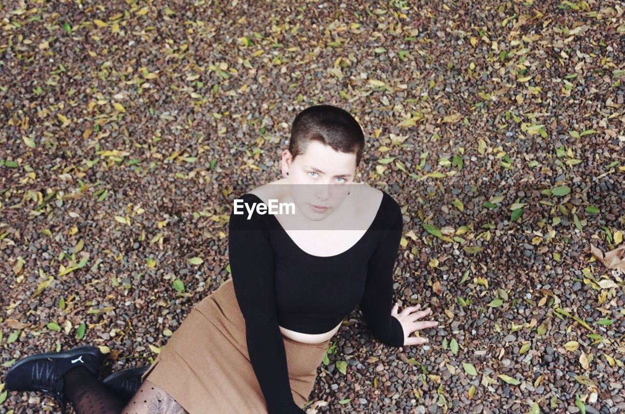 High angle portrait of young woman sitting on field