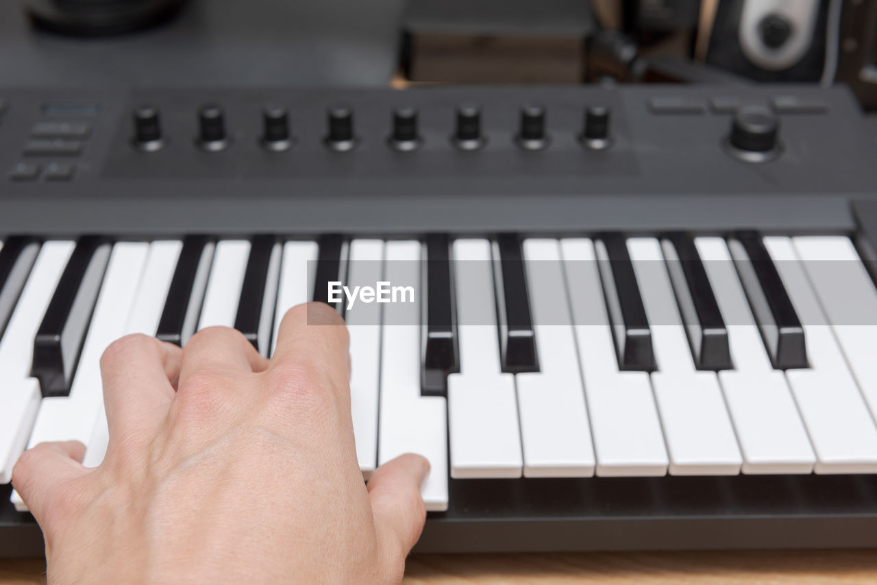 Close-up of hand playing piano