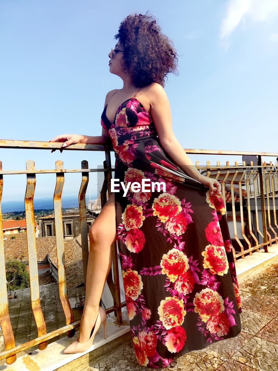 Woman standing by railing against sky