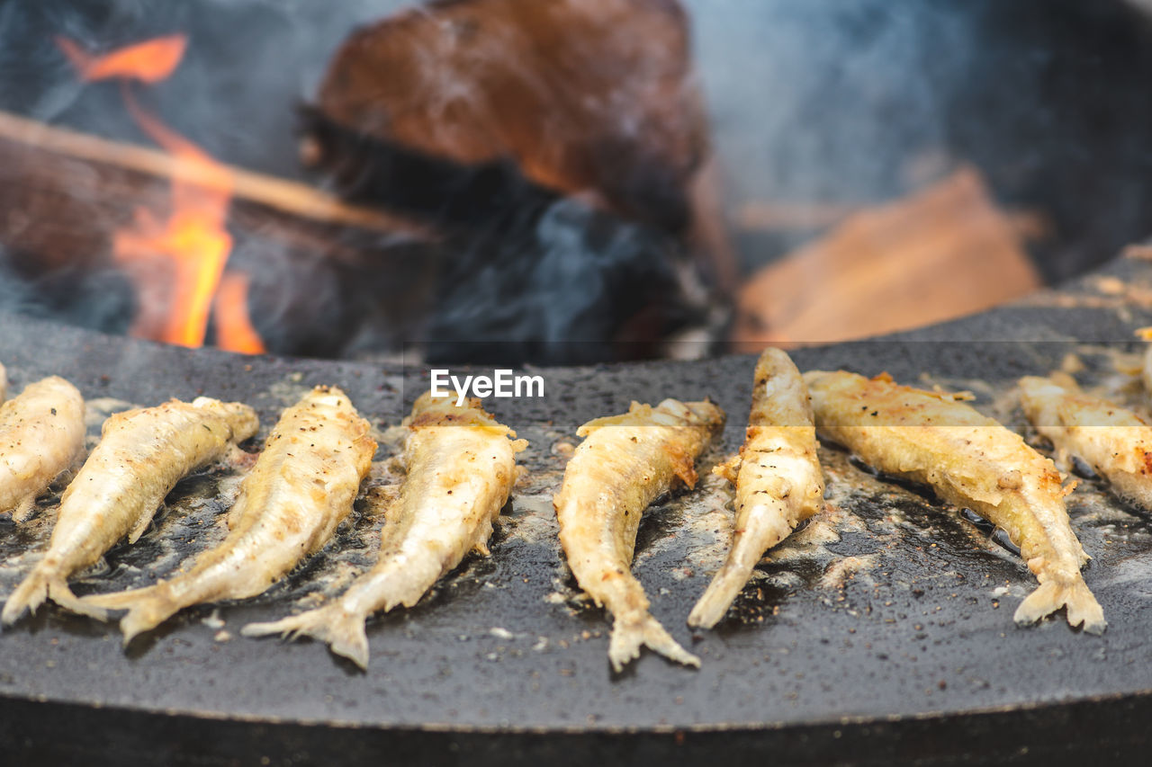 Preparing traditional tasty fried european smelt fish cooked on an open fire in a street food market