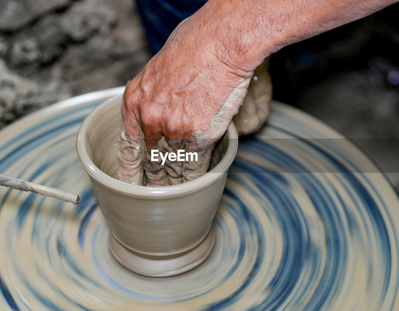 Cropped hand of man making pottery on pottery wheel in workshop