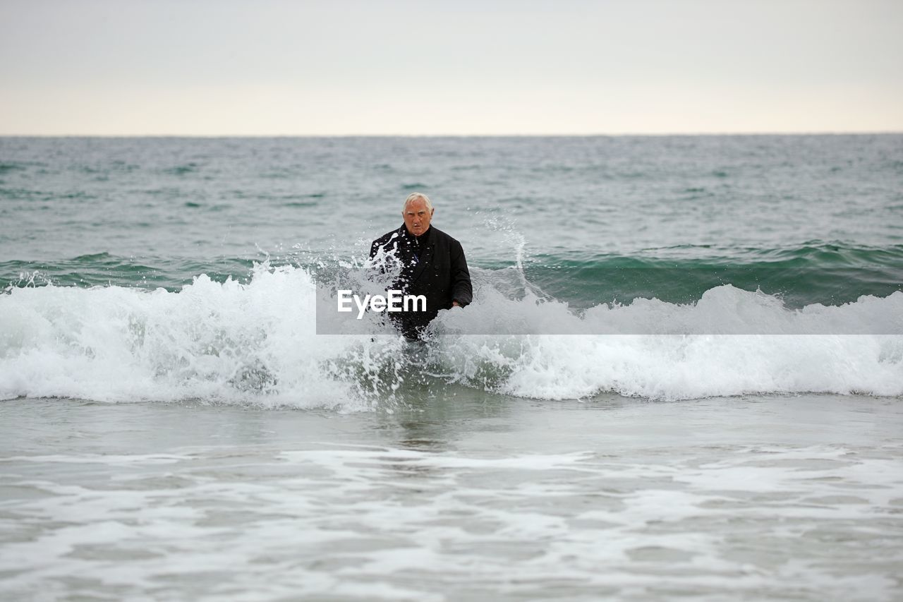 Man wading in sea against sky