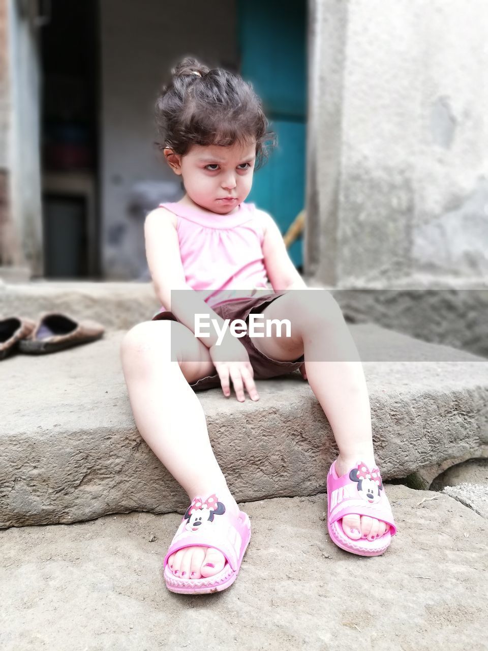 CUTE GIRL SITTING IN PINK WHILE LOOKING AT CAMERA