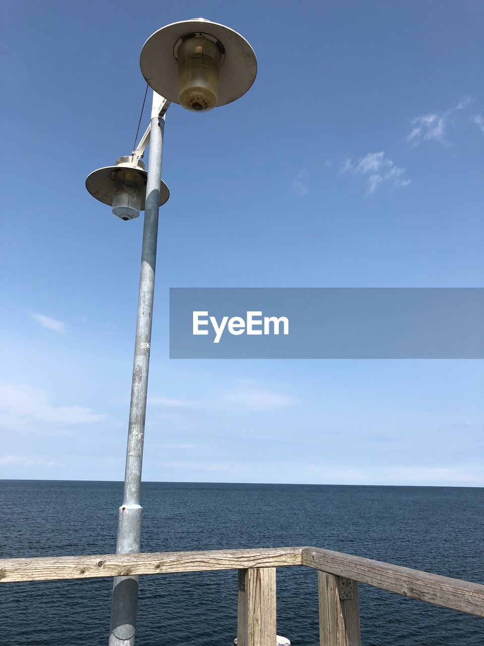 Low angle view of street light by sea against sky