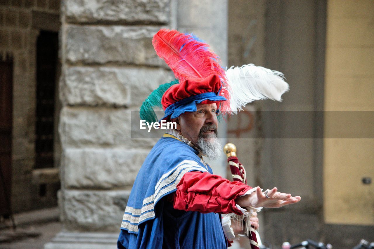 SIDE VIEW OF PERSON WEARING RED UMBRELLA STANDING AGAINST WALL