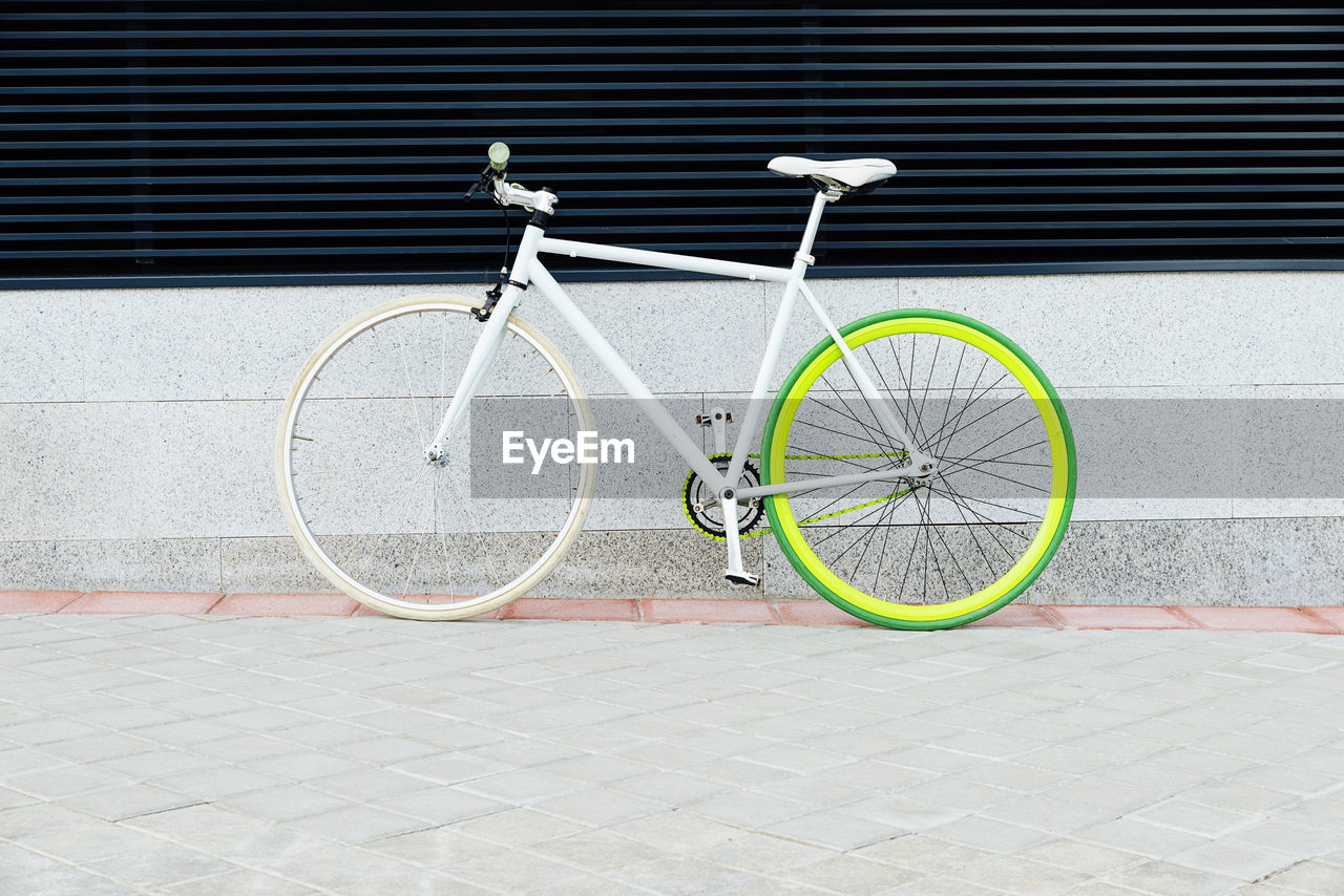 Bicycle parked on footpath against wall