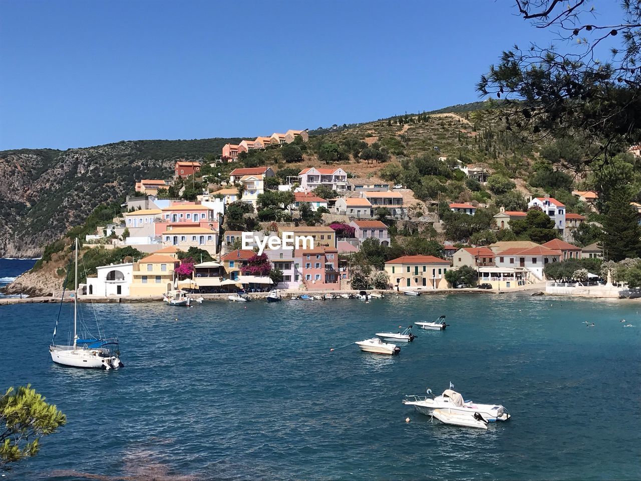 Sailboats in sea by townscape against clear sky