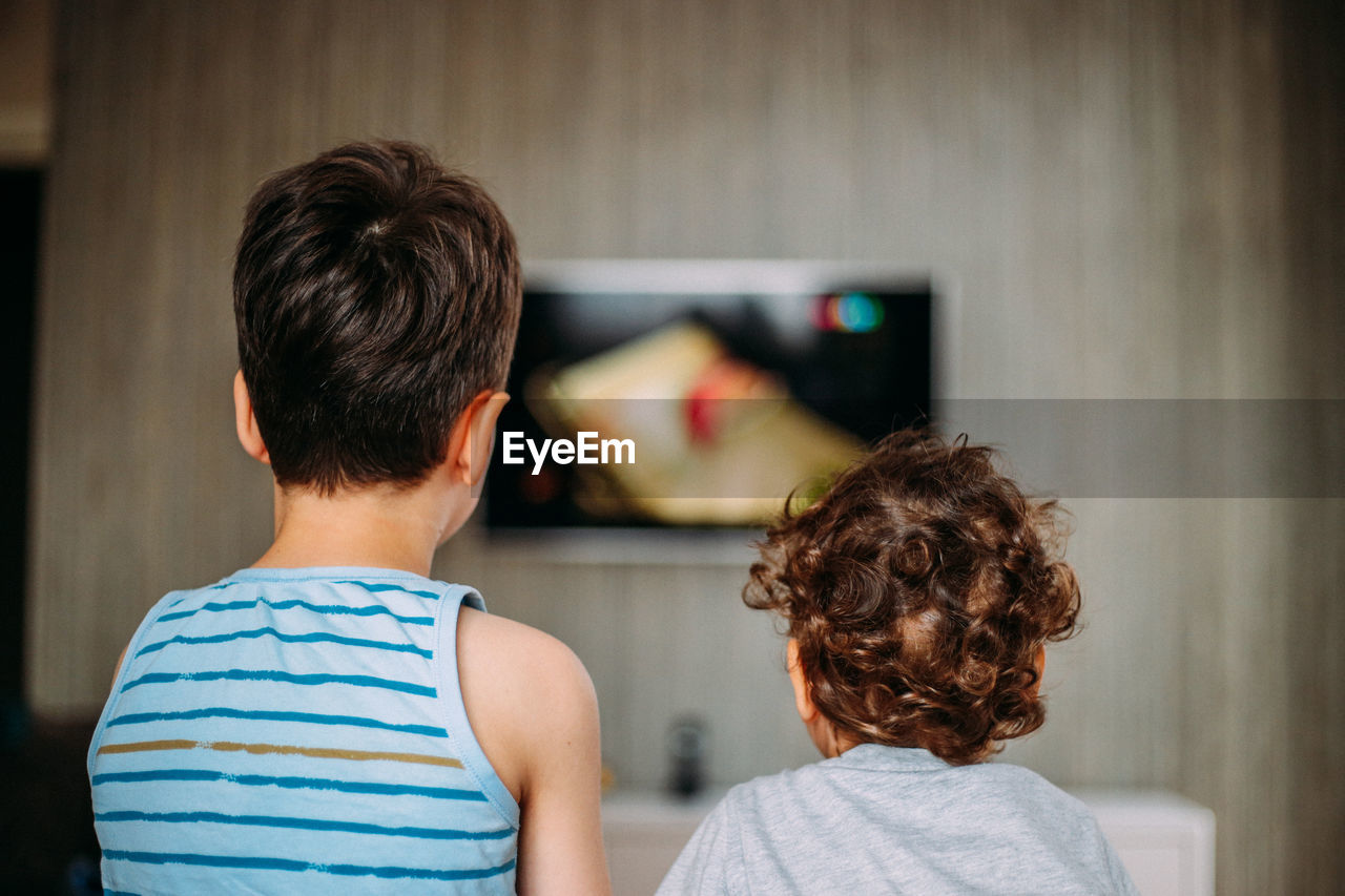 Two boys are watching an interesting tv show on tv. children's home rest. home activity. 