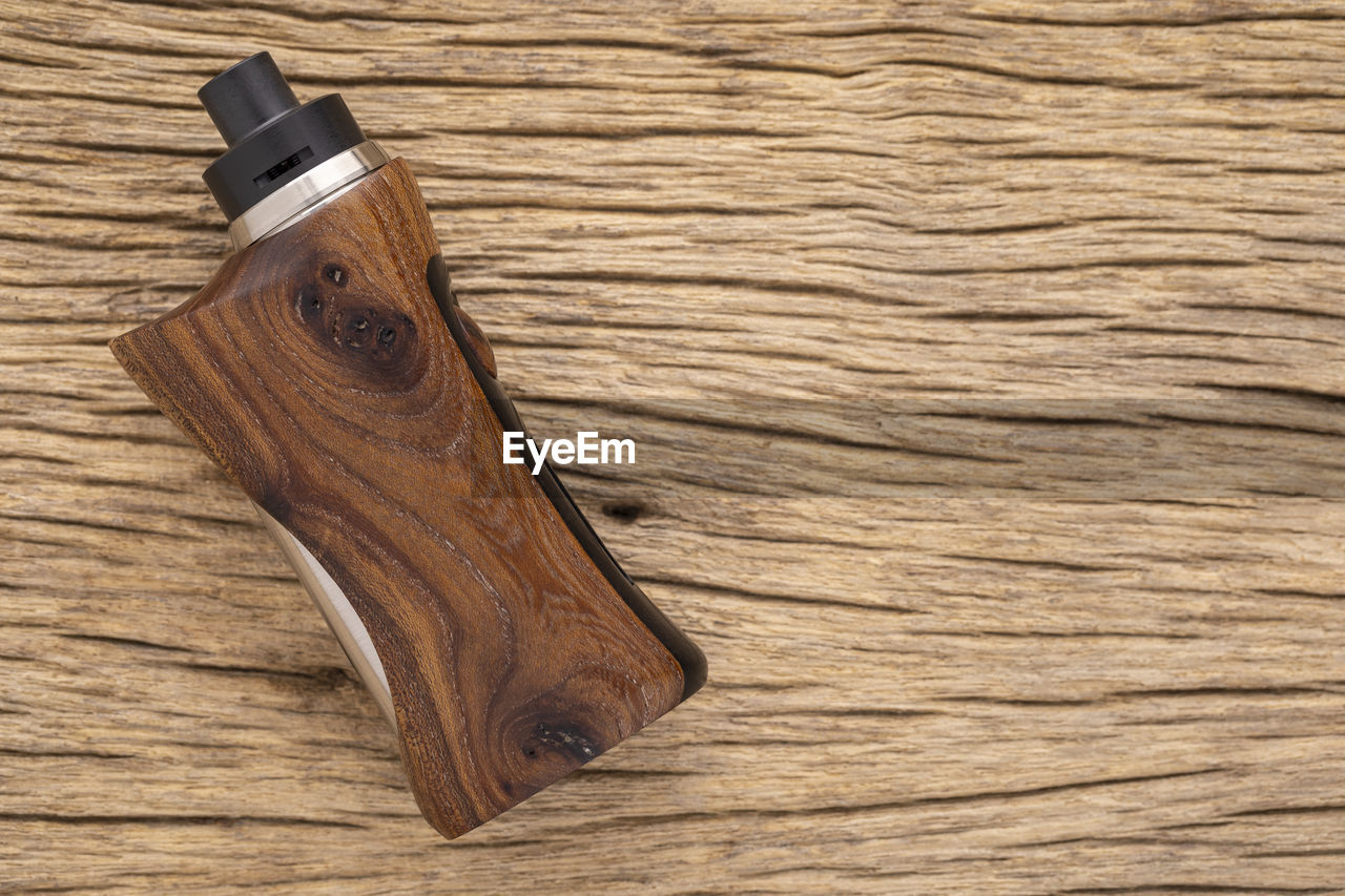 Rebuildable dripping atomizer with stabilized wood regulated box mods on natural wood background