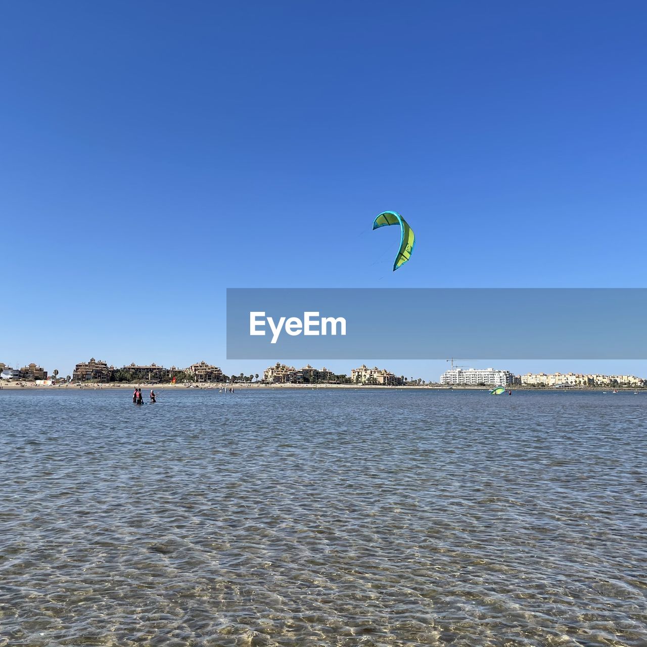 PEOPLE PARAGLIDING IN SEA AGAINST CLEAR SKY