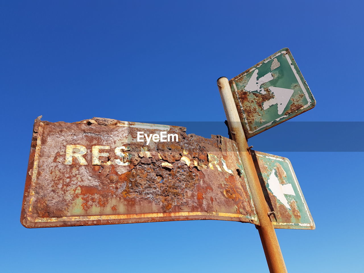 LOW ANGLE VIEW OF OLD RUSTY METAL AGAINST CLEAR BLUE SKY