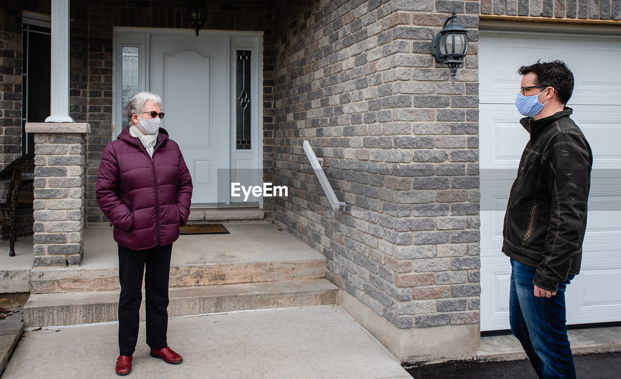 Man and older woman talking while wearing face masks during covid 19.