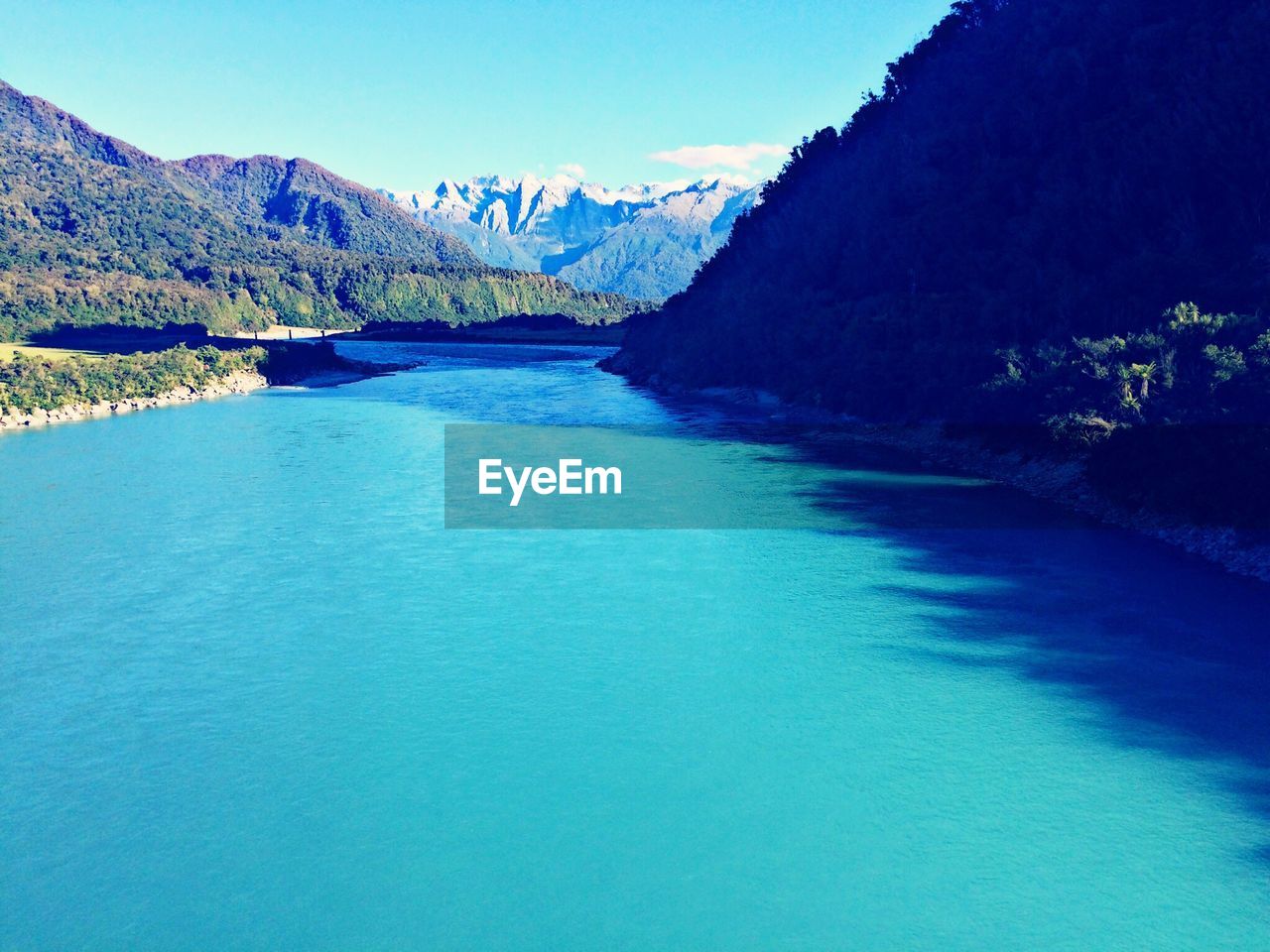 SCENIC VIEW OF RIVER BY MOUNTAINS AGAINST CLEAR BLUE SKY