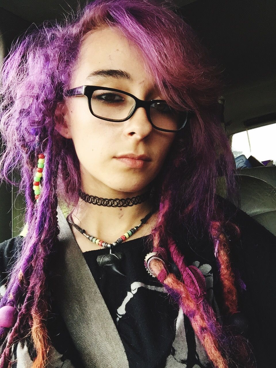 Low angle portrait of woman with dreadlock hair sitting in car