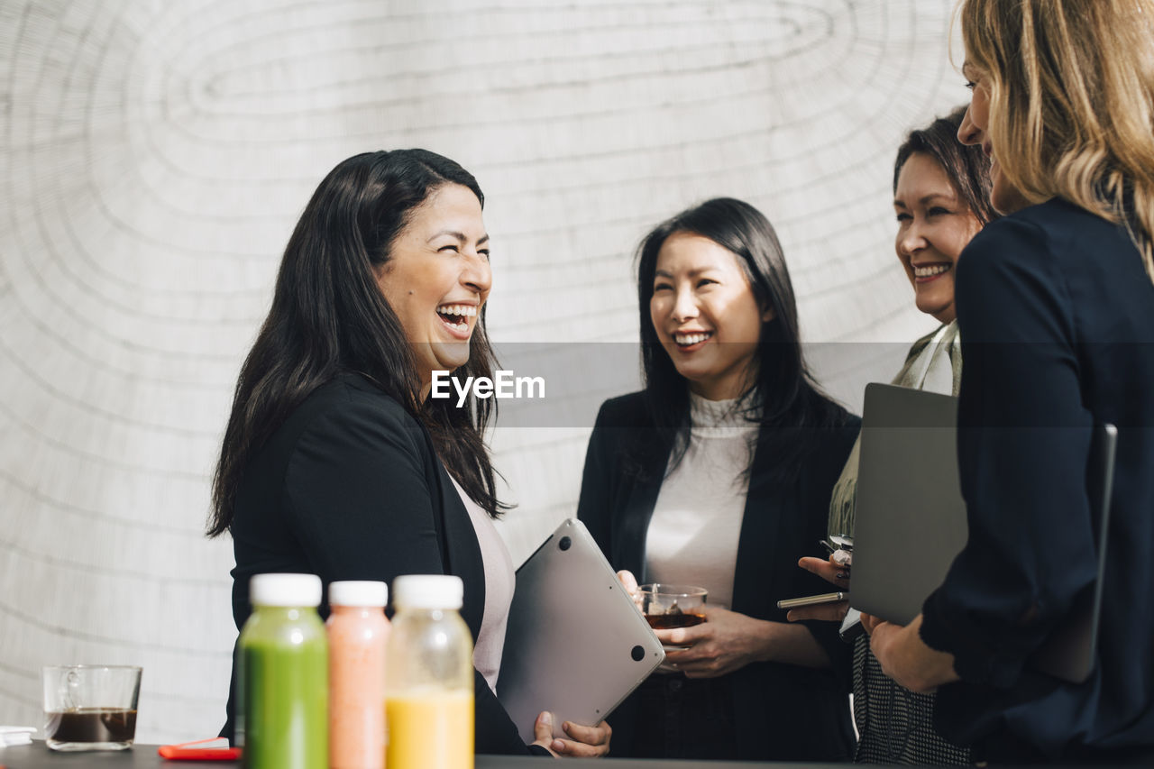 Cheerful female professionals networking in conference meeting at office